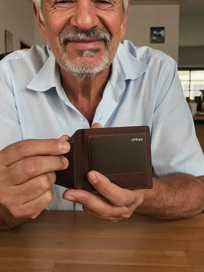 Hombre mostrando una tarjeta ohkax dentro de su cartera de piel